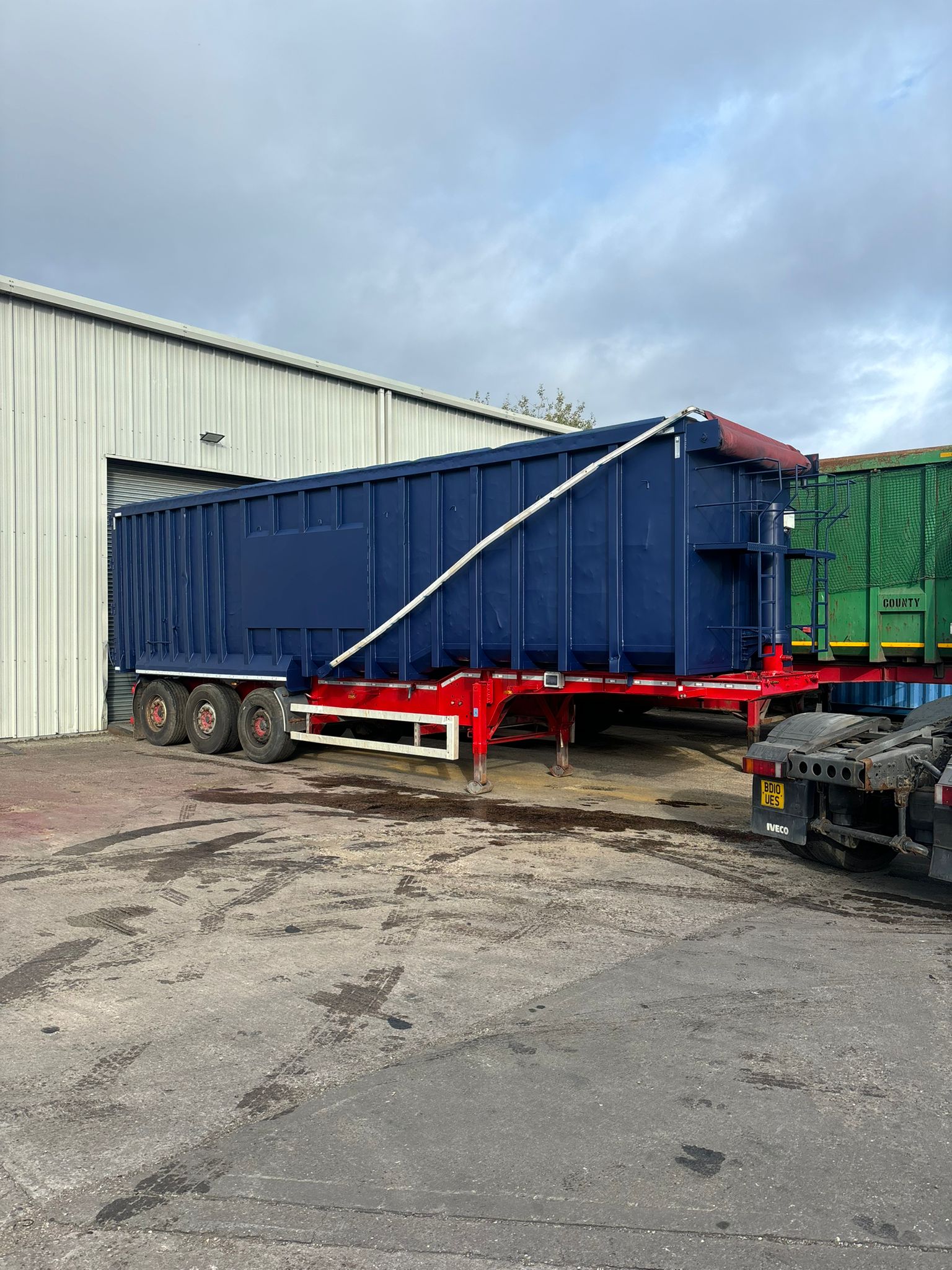 Refurbished navy tipping trailer with red chassis outside the Draycott Commercials workshop